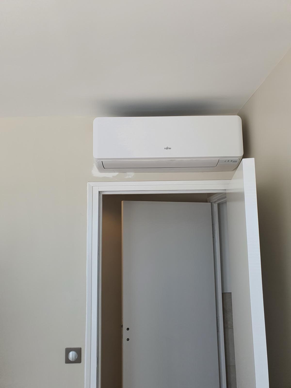 Unité de climatisation murale Fujitsu installée au-dessus d’une porte